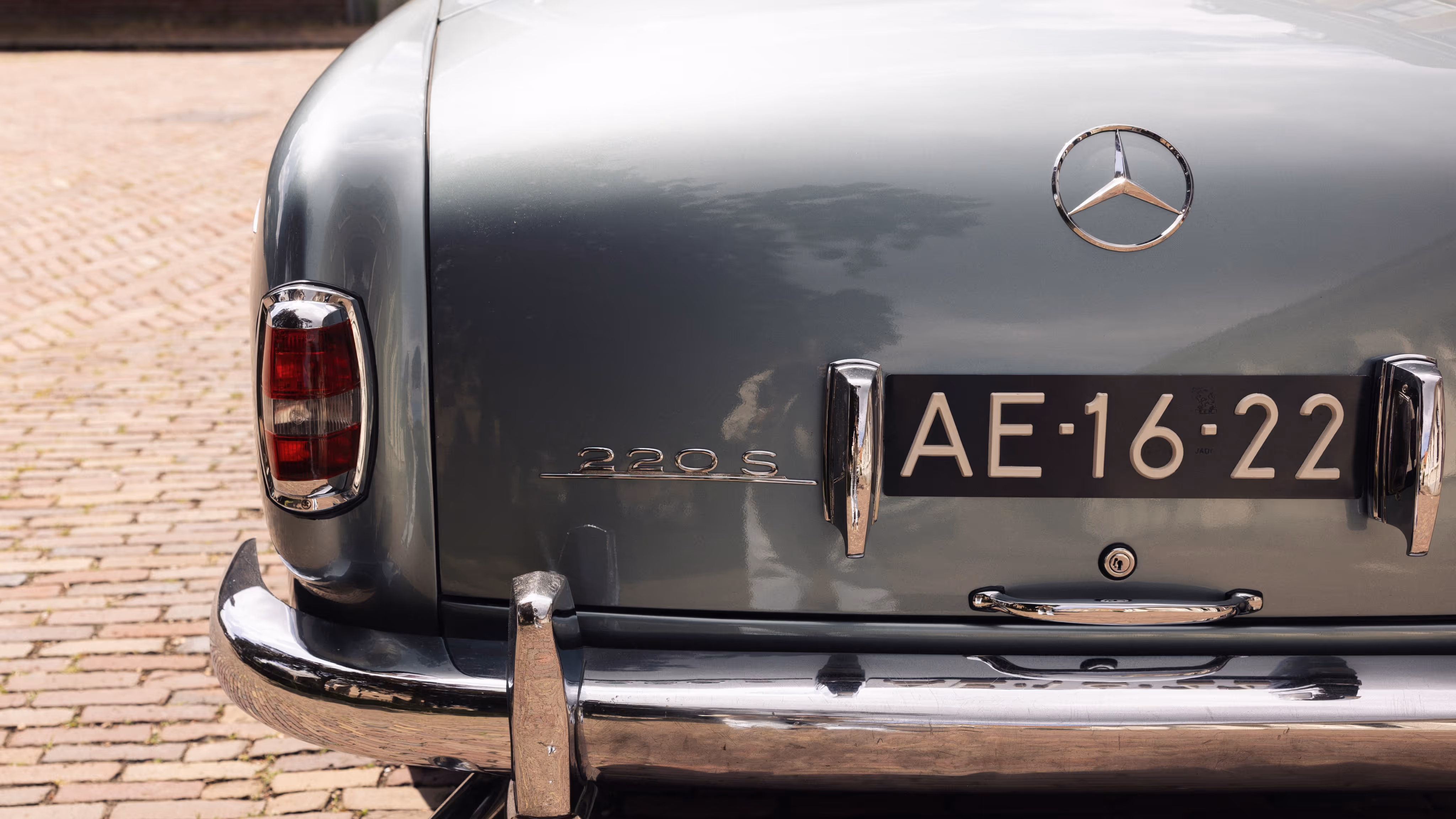 Klassieke borgo Mercedes 220S trouwauto met chroom details op bestrating