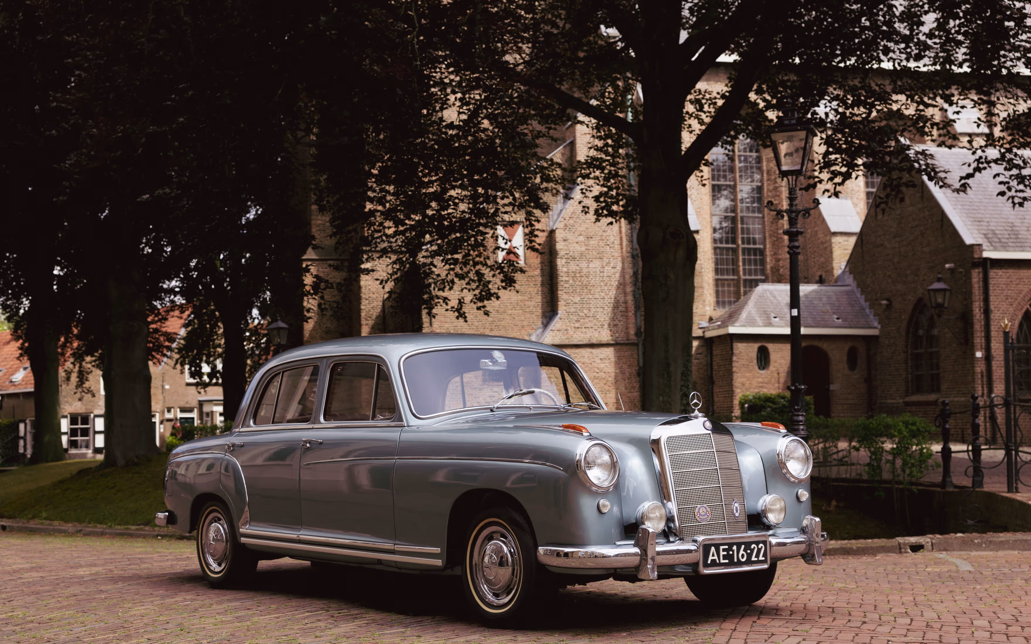 Klassieke Mercedes trouwauto in borgo met oude kerk op de achtergrond