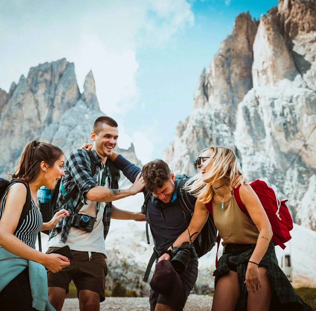 Four friends trekking together and laughing.