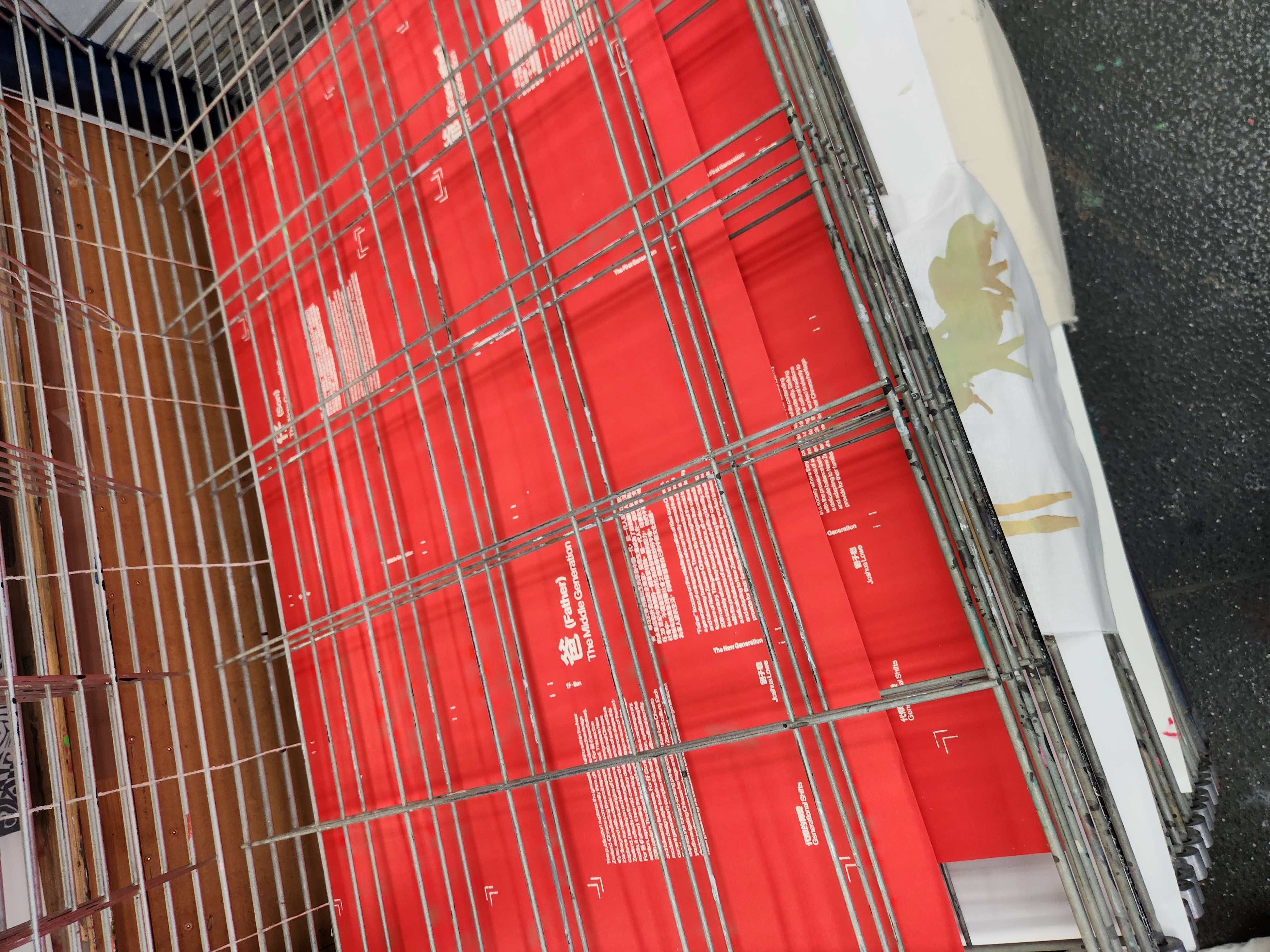 Metal drying rack holding several red posters with white text about 'Father (The Middle Generation)' and 'Generational Shifts'.