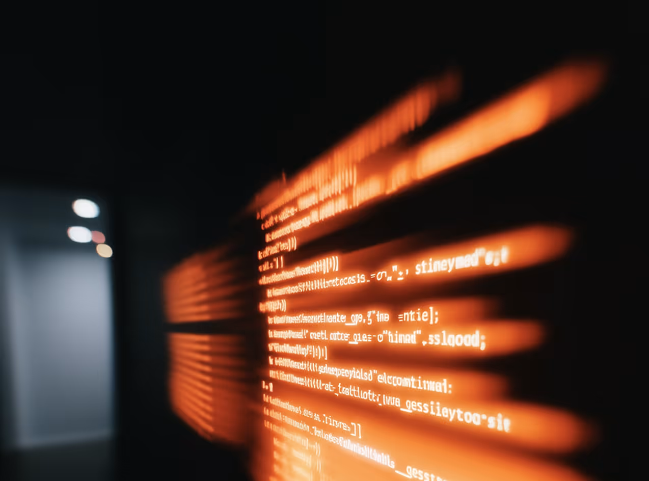 Blurry orange coding text projected on a dark wall with bright lights in background.