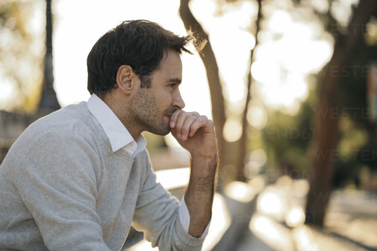 A man deep in thought while sitting outdoors.