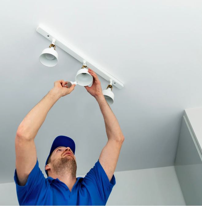 Electrician installing ceiling-mounted LED lighting fixtures as part of residential lighting services.