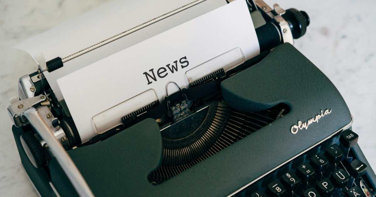 Machine à écrire verte vintage sur une table tapant le mot "News" — objet de collection emblématique et symbole de communication dans l’univers des collectionneurs.