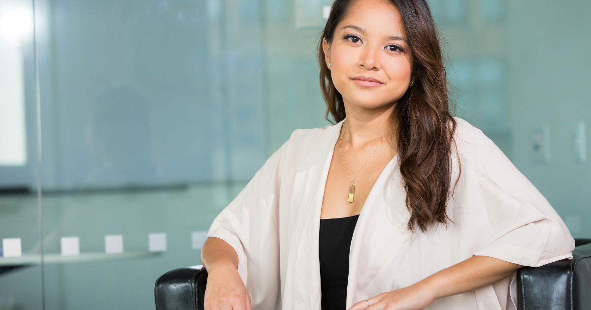 Femme typée asiatique souriante assise avec une blouse blanche