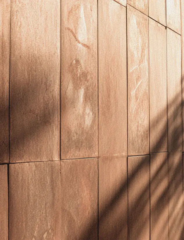 Close-up of tan rectangular stone tiles with shadows cast across them.