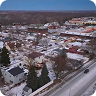 Aerial view of a street with cars, trees, and people walking on the sidewalk and plaza.