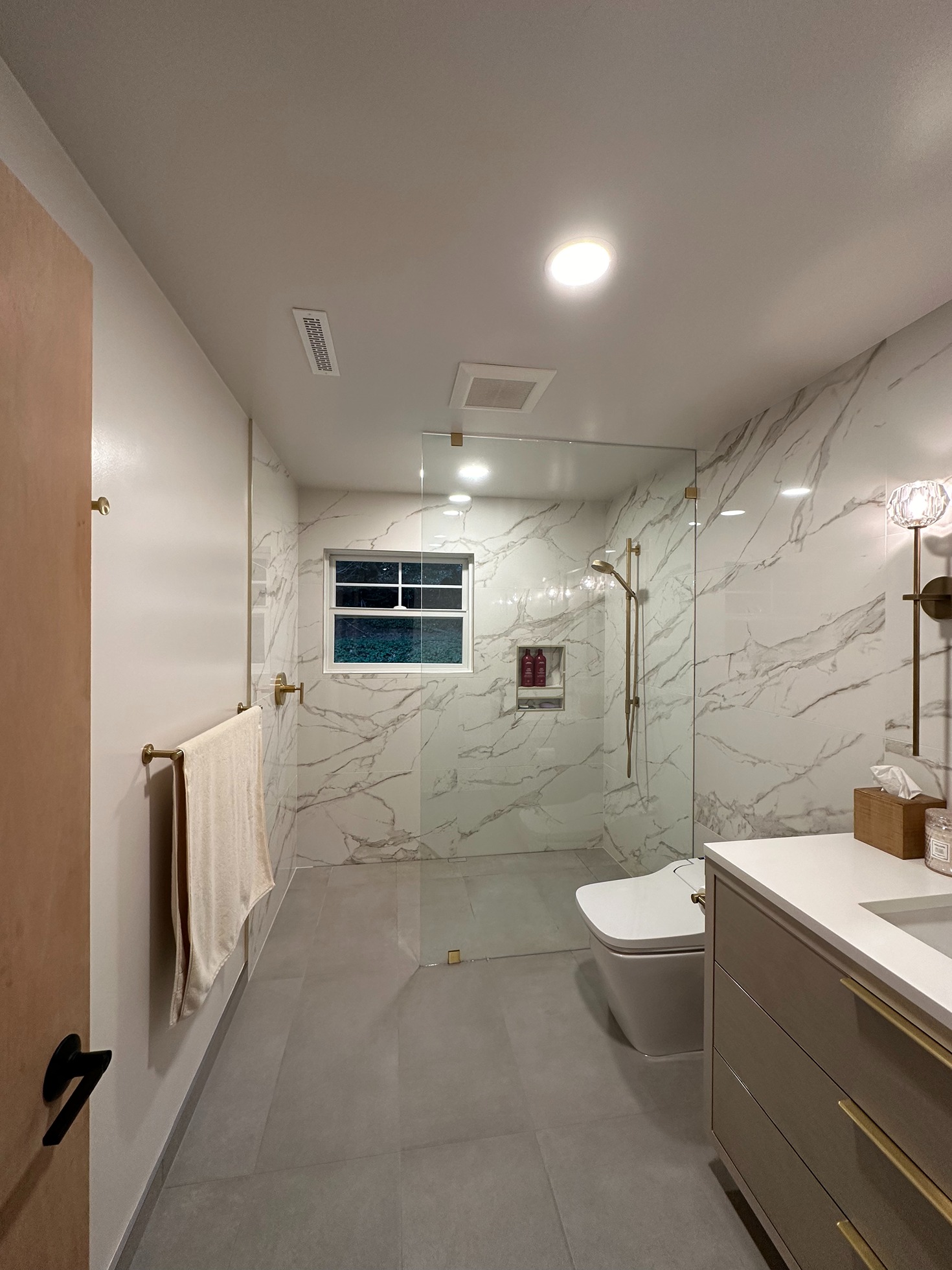 Modern bathroom remodel with a spacious glass shower, white subway tile walls, and a dark wood vanity with granite countertop and mounted mirror