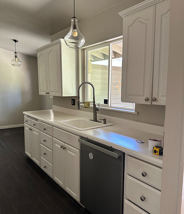 Before—dated white kitchen cabinets in narrow galley, uneven layout, limited storage