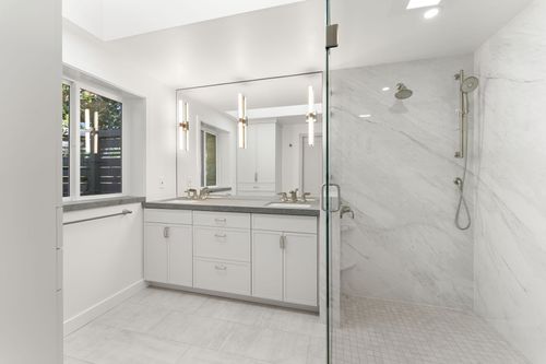 Remodeled walk-in shower with mosaic and quartz tile, custom-lit vanity mirror, and built-in cabinetry in a Brier home.