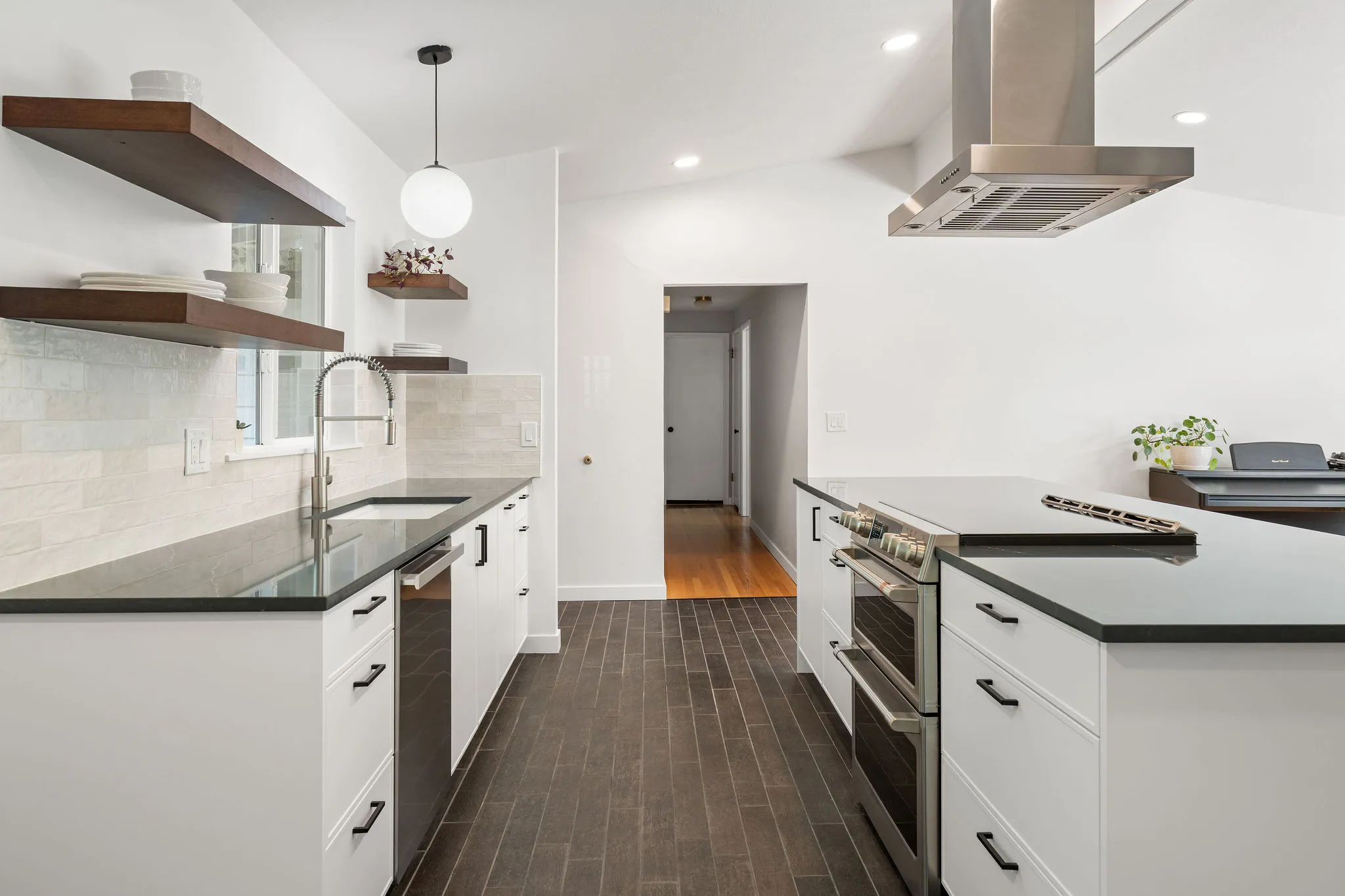 Remodeled galley kitchen in Woodinville with white shaker cabinets, black quartz counters, and walnut floating shelves