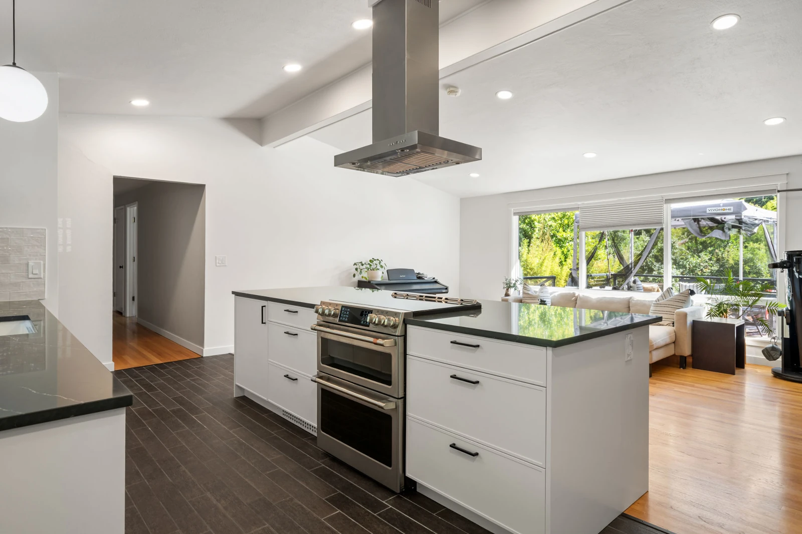 Remodeled Mill Creek, WA kitchen with a granite countertop, gas range, and overhead range hood.