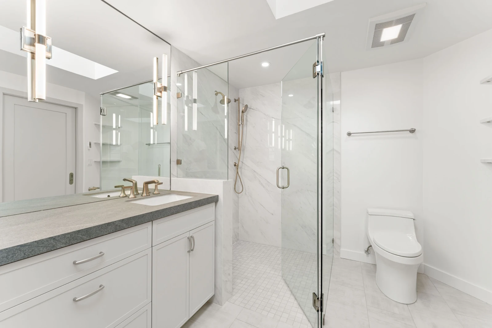 Bathroom remodel in a North Seattle, WA home with a walk-in tile shower, toilet, and natural stone countertop.