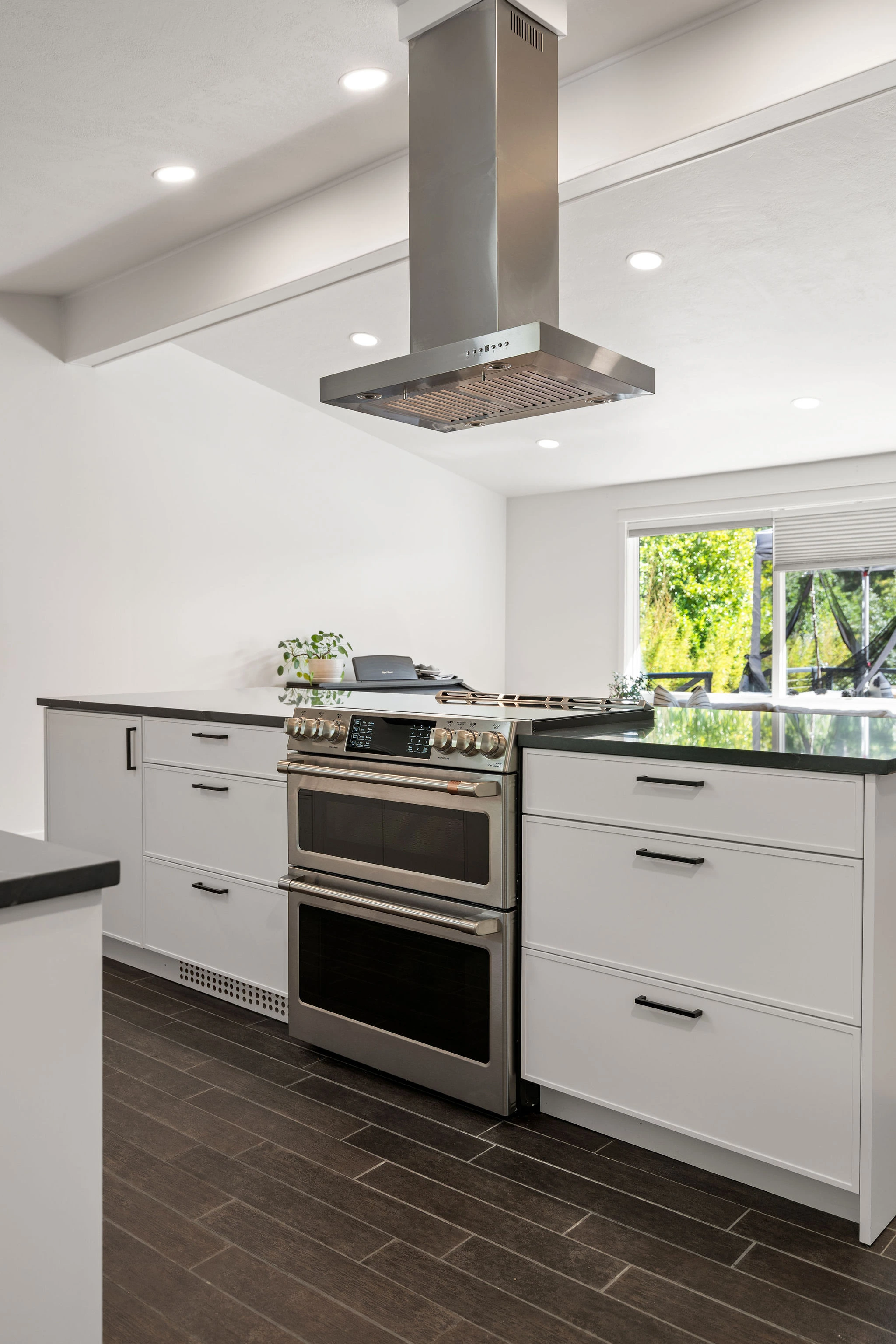 Remodeled kitchen island featuring a stainless steel double oven, range hood, and matte black cabinet hardware.