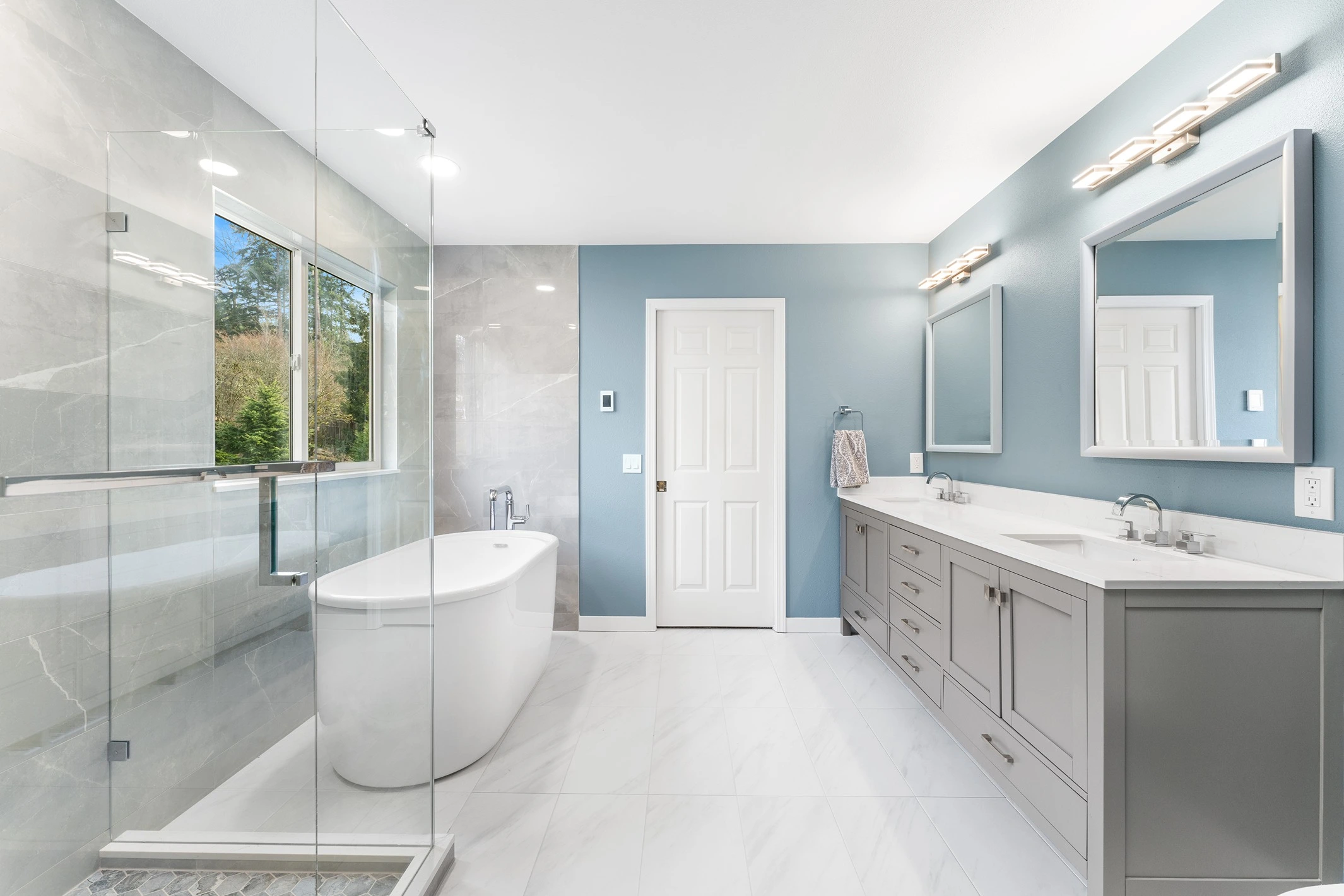 Bathroom remodel with a walk-in shower, large-format stone-look wall tile, and a double vanity with two mirrors, from a recent project near Mercer Island.