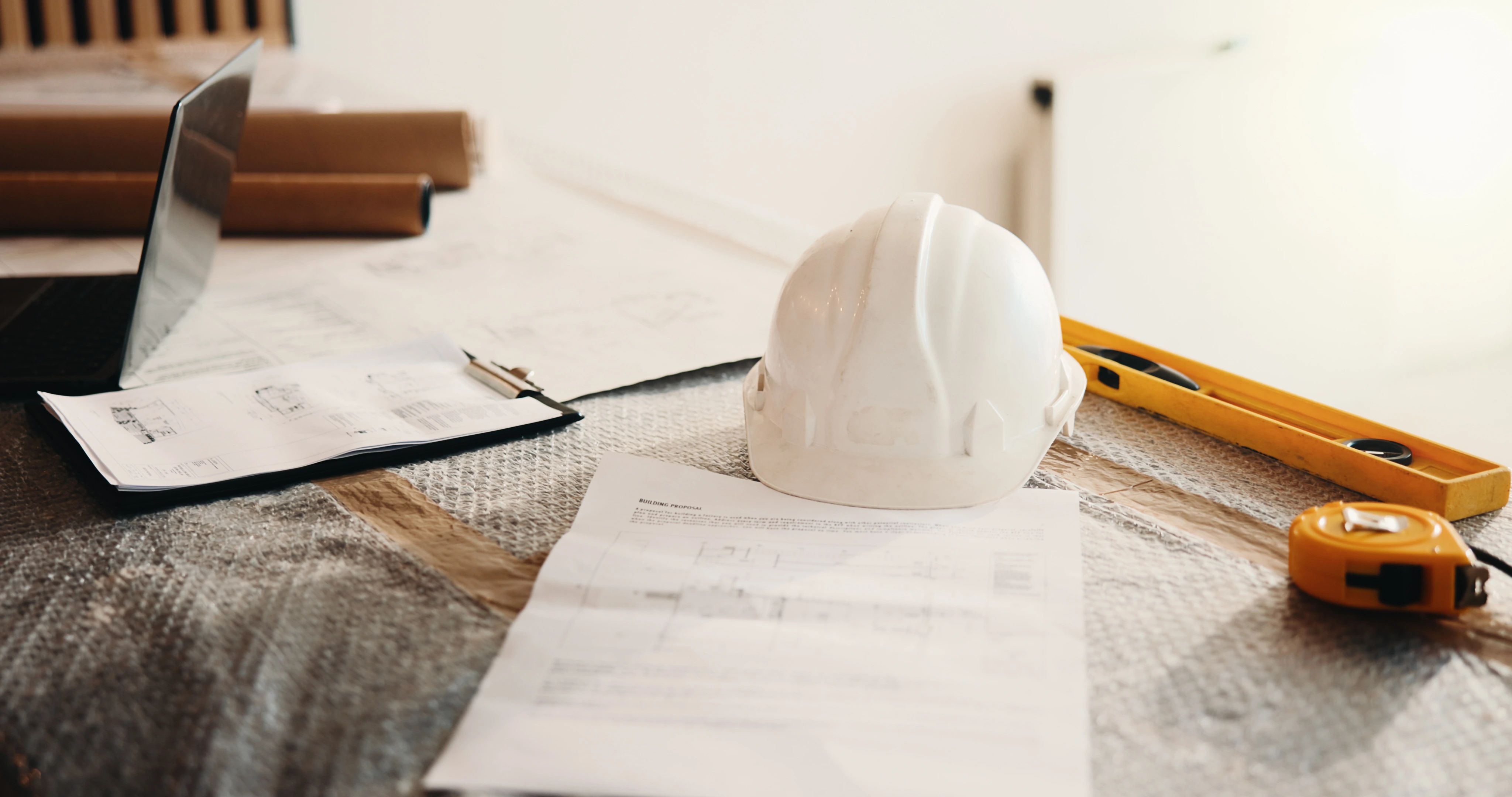 Home remodel permit application documents and architectural blueprints laid out with contractor tools for plan review.