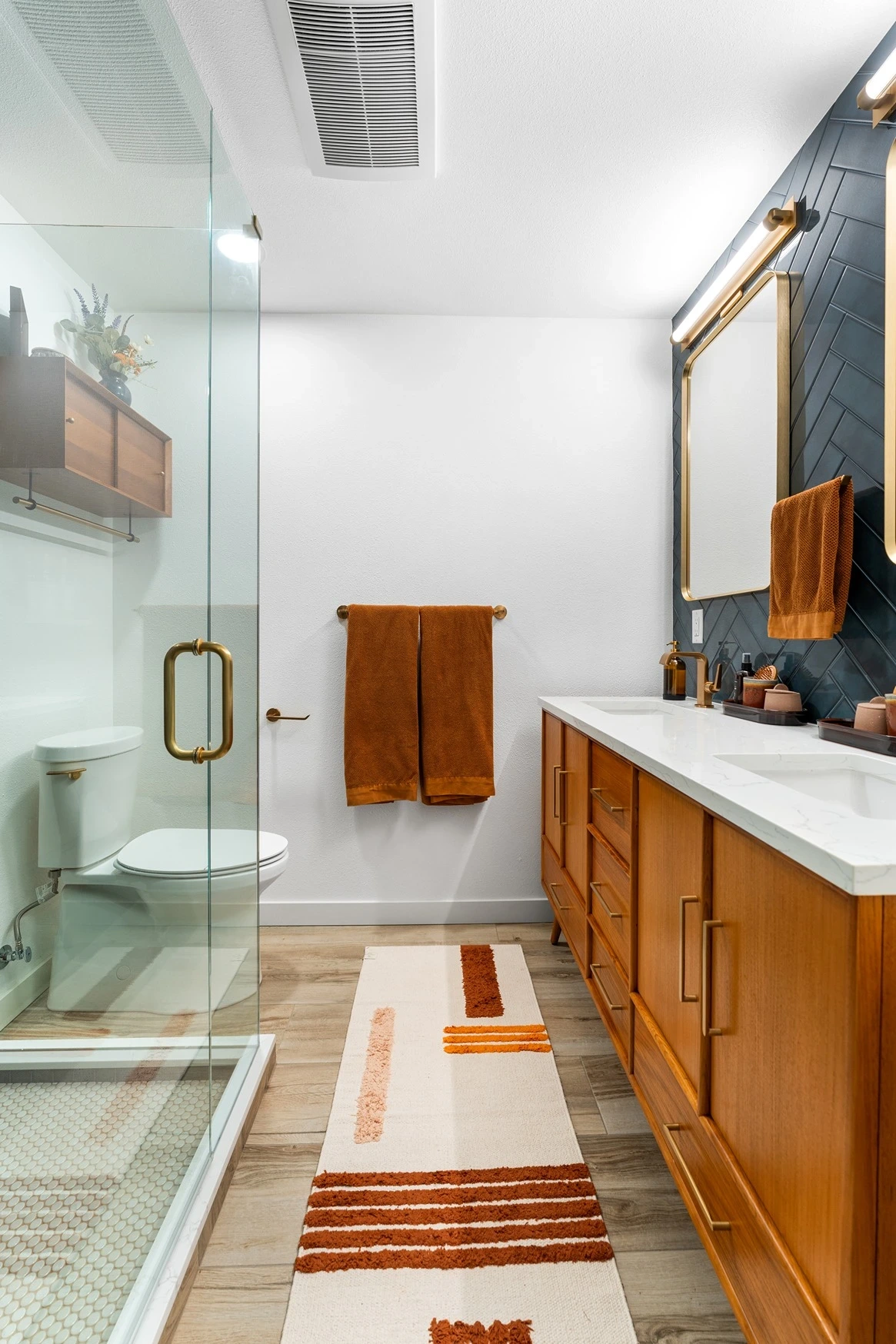 Bathroom with a wood vanity, walk-in glass shower, and blue accent tile