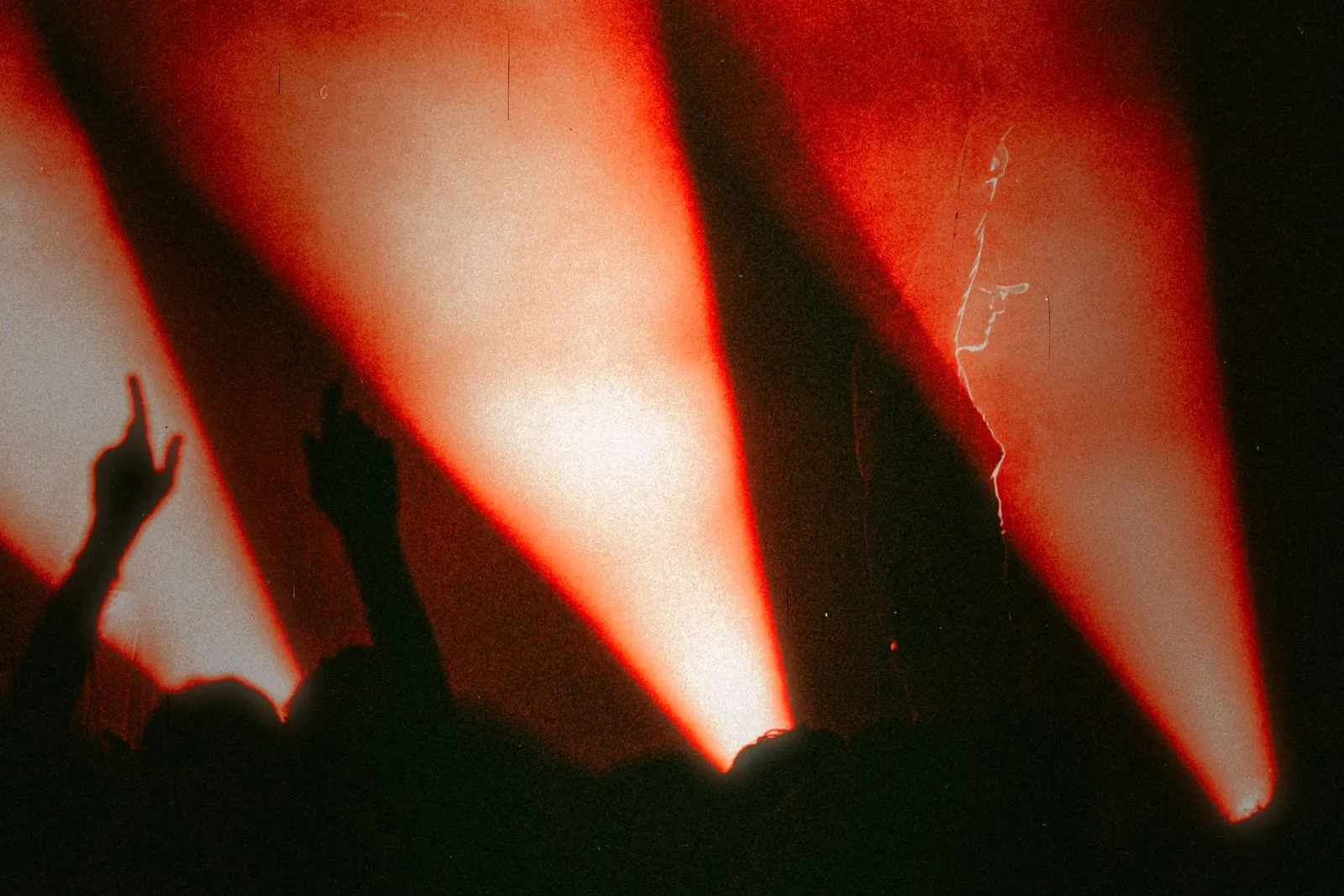 Menschenmenge vor roten Bühnenlichtern, einige mit erhobenen Händen bei Konzert oder Event von Edo Saiya. Foto/Video von Felix Weise, Medienproduktion für Sport, Outdoor & Events im Allgäu, Kempten und Bayern.