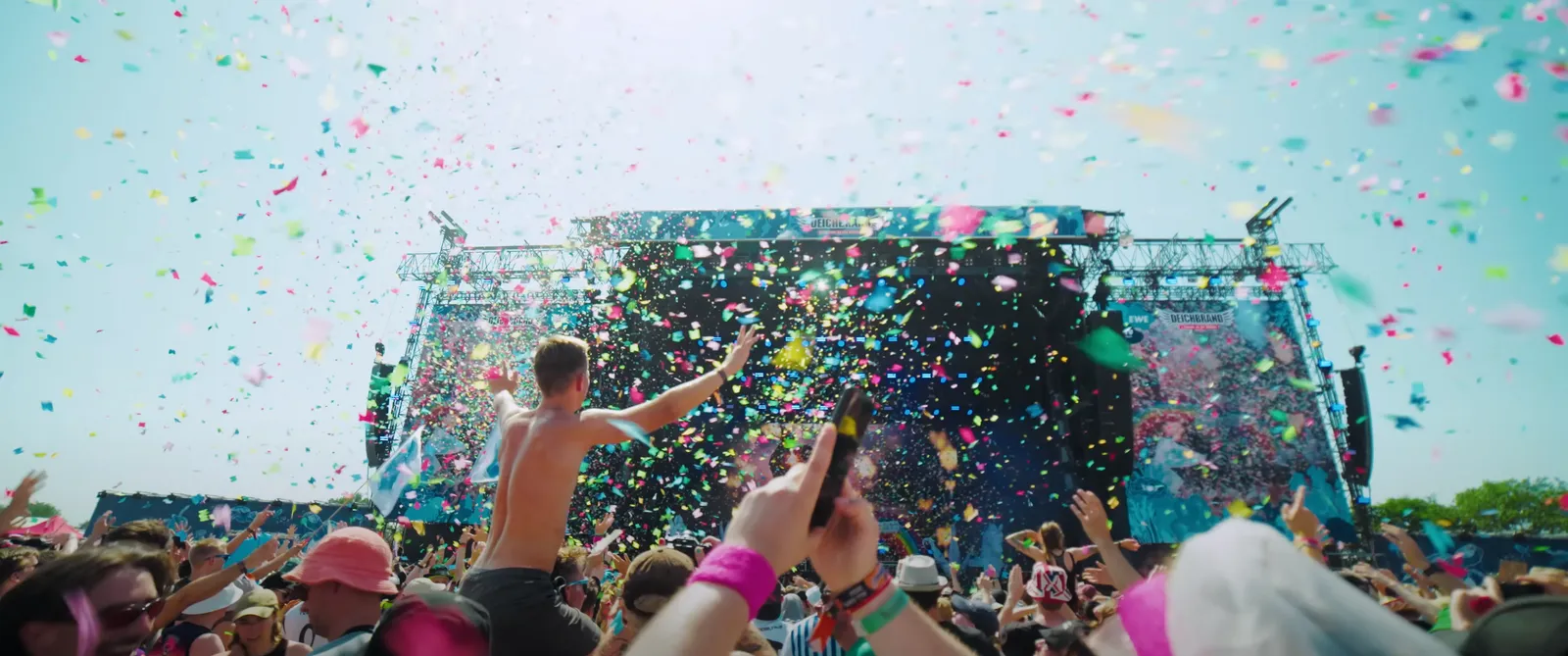 Menschenmenge bei einem Festival mit Konfetti und einer großen Bühne im Hintergrund. Foto/Video von Felix Weise, Medienproduktion für Sport, Outdoor & Events im Allgäu, Kempten und Bayern.