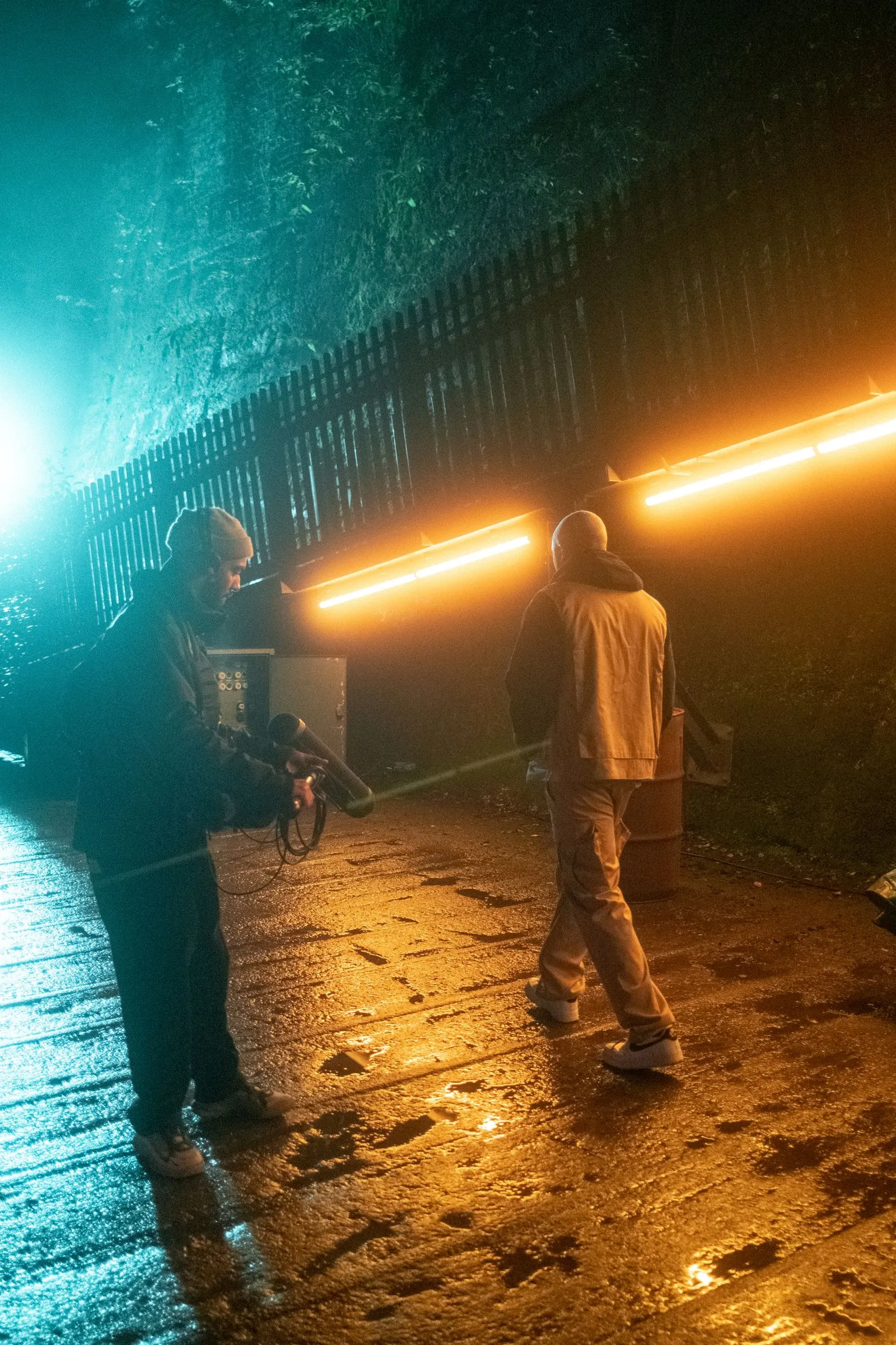 Zwei Männer draußen am Abend, einer hält Mikrofon, die Szene ist mit orange und blau beleuchtet. Foto/Video von Felix Weise, Medienproduktion für Sport, Outdoor & Events im Allgäu, Kempten und Bayern.