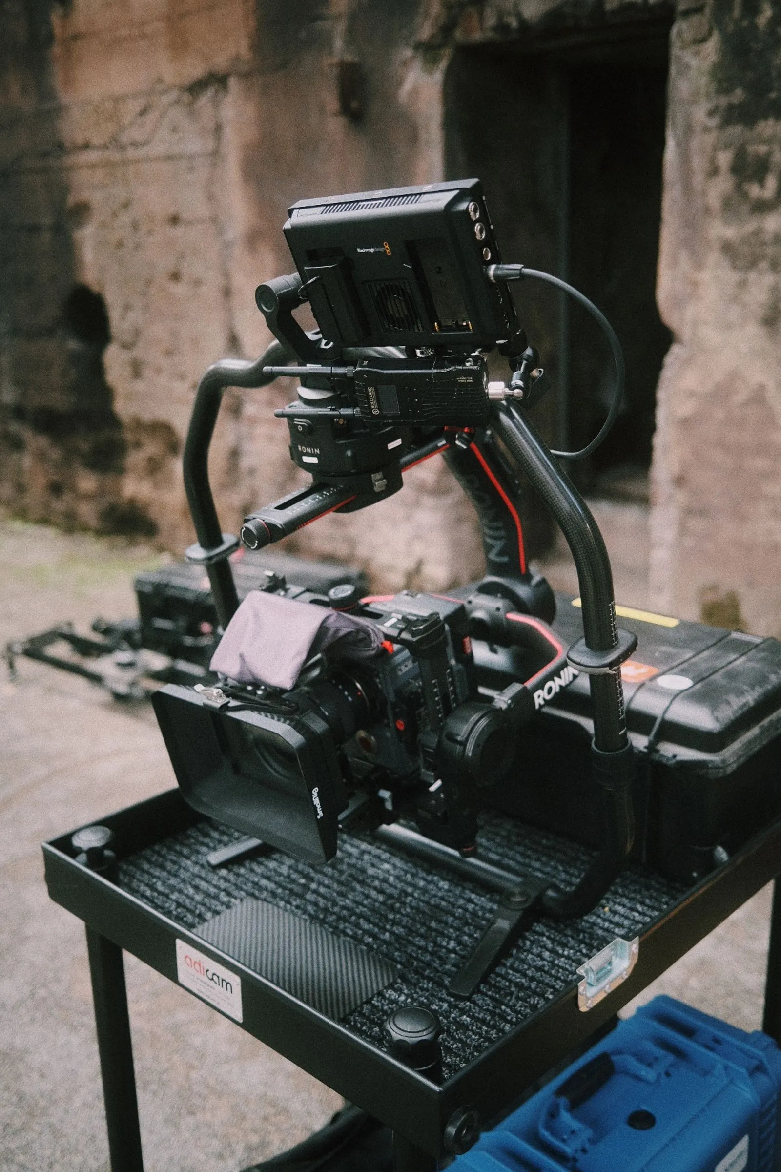 Professionelle Kamera mit Gimbal-Stabilisator von Ronin auf einem Tisch mit Equipment. Foto/Video von Felix Weise, Medienproduktion für Sport, Outdoor & Events im Allgäu, Kempten und Bayern.