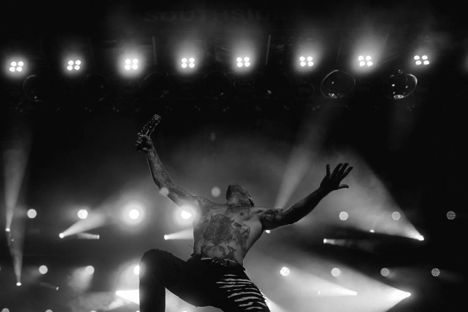 Kontra K mit Mikrofon hebt Arme bei Konzert mit Bühnenlichtern im Hintergrund. Foto/Video von Felix Weise, Medienproduktion für Sport, Outdoor & Events im Allgäu, Kempten und Bayern.