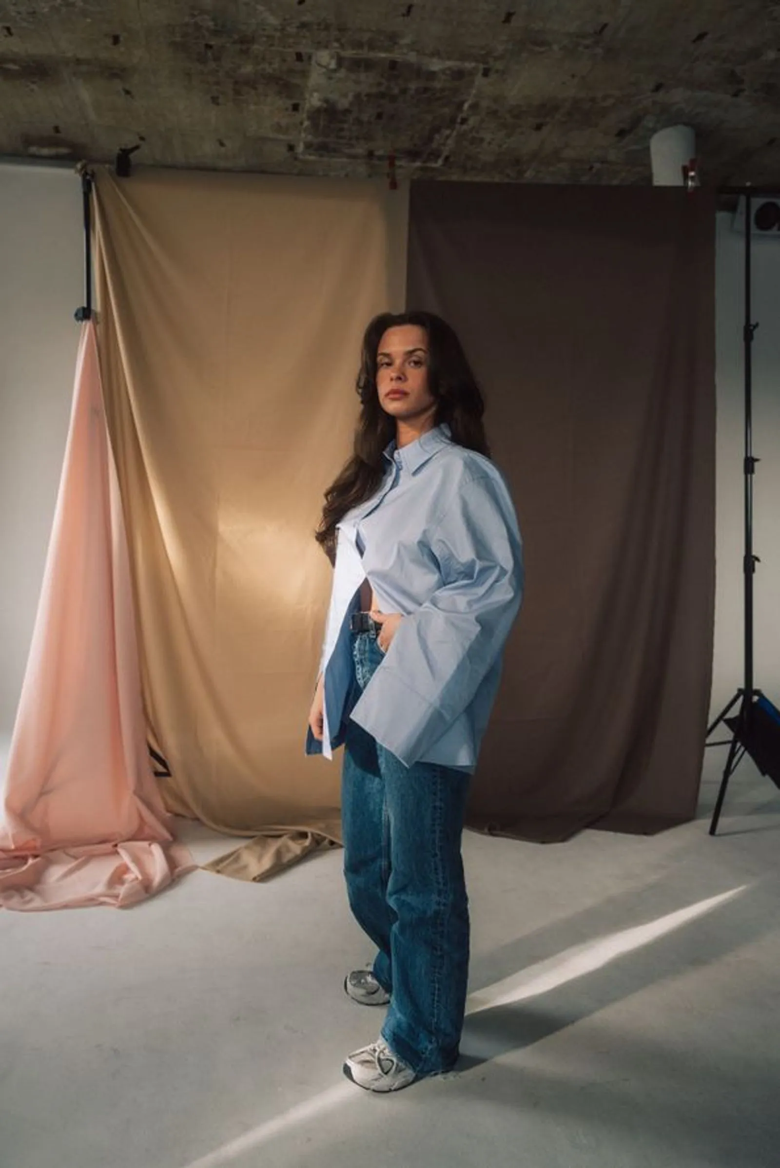 Frau mit offenem hellblauem Hemd, Jeans und Turnschuhen vor Stoffhintergrund in Studio.
Foto/Video von Felix Weise, Medienproduktion für Sport, Outdoor & Events im Allgäu, Kempten und Bayern.
