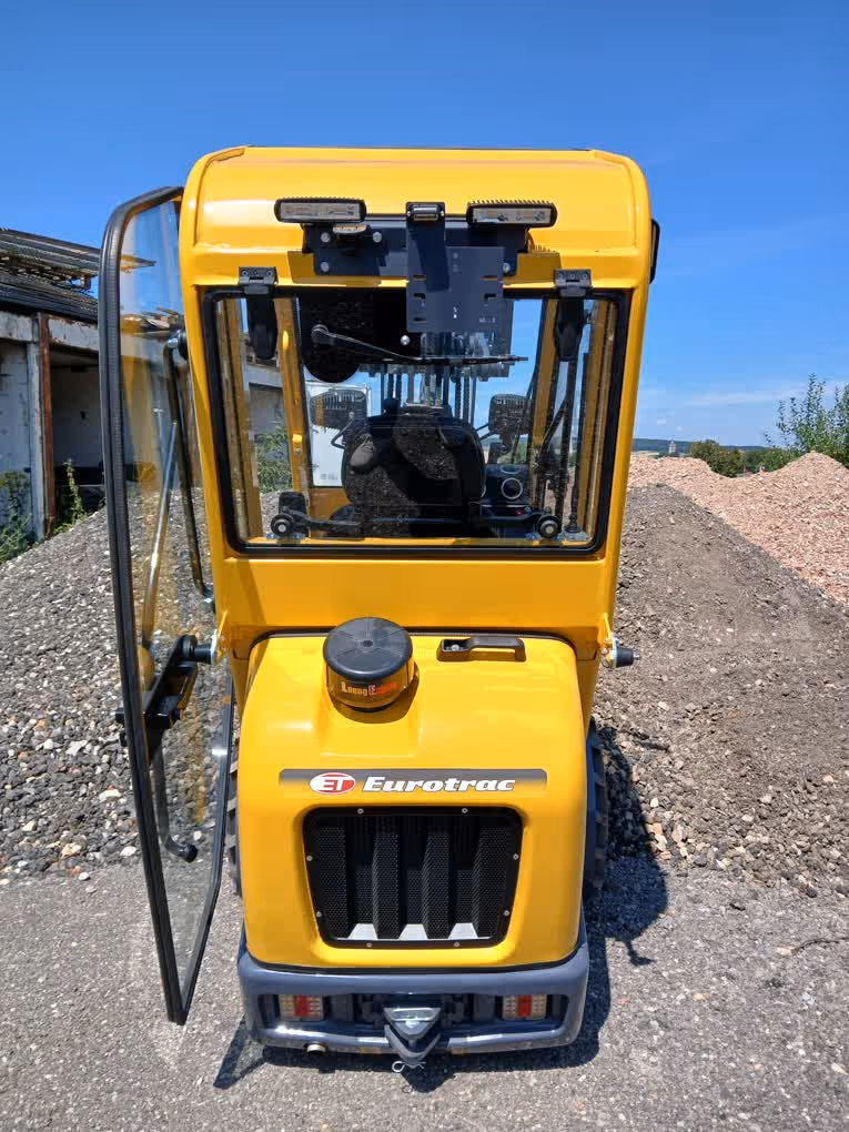 Eurotrac Baumaschine von Sadema GmbH im Einsatz, moderner Hoflader oder Minibagger mit Schaufel und Hydraulik, gelbes robustes Fahrzeug auf Baustelle oder Hof, kompakte Bauweise, starke Leistung und zuverlässige Technik für Landwirtschaft und Bau.