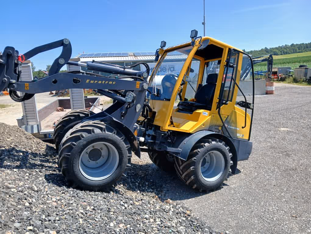 Eurotrac Baumaschine von Sadema GmbH im Einsatz, moderner Hoflader oder Minibagger mit Schaufel und Hydraulik, gelbes robustes Fahrzeug auf Baustelle oder Hof, kompakte Bauweise, starke Leistung und zuverlässige Technik für Landwirtschaft und Bau.