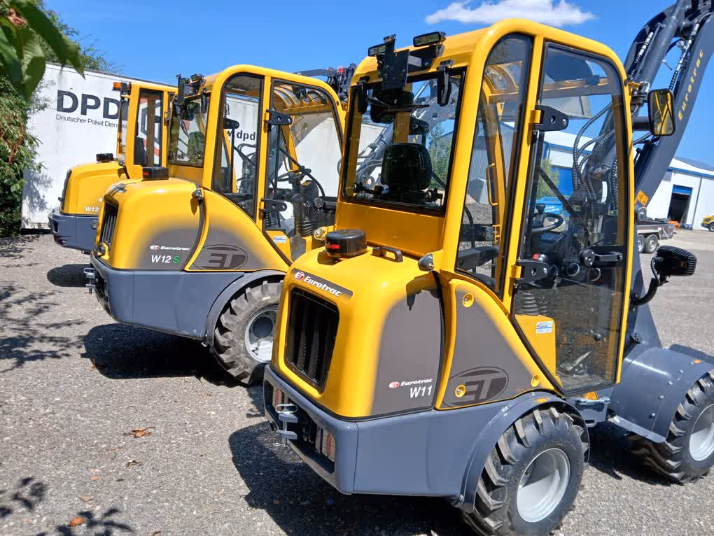 Eurotrac Baumaschine von Sadema GmbH im Einsatz, moderner Hoflader oder Minibagger mit Schaufel und Hydraulik, gelbes robustes Fahrzeug auf Baustelle oder Hof, kompakte Bauweise, starke Leistung und zuverlässige Technik für Landwirtschaft und Bau.