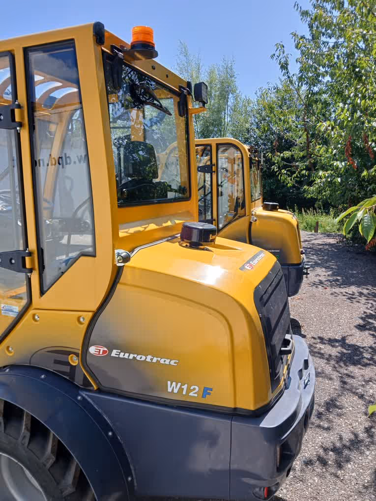 Eurotrac Baumaschine von Sadema GmbH im Einsatz, moderner Hoflader oder Minibagger mit Schaufel und Hydraulik, gelbes robustes Fahrzeug auf Baustelle oder Hof, kompakte Bauweise, starke Leistung und zuverlässige Technik für Landwirtschaft und Bau.