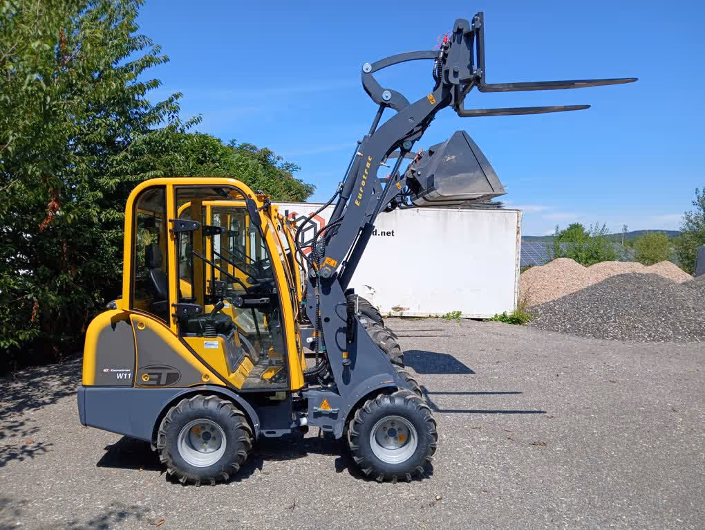 Eurotrac Baumaschine von Sadema GmbH im Einsatz, moderner Hoflader oder Minibagger mit Schaufel und Hydraulik, gelbes robustes Fahrzeug auf Baustelle oder Hof, kompakte Bauweise, starke Leistung und zuverlässige Technik für Landwirtschaft und Bau.
