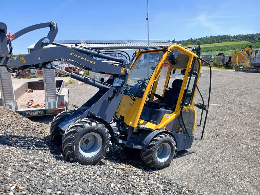 Eurotrac Baumaschine von Sadema GmbH im Einsatz, moderner Hoflader oder Minibagger mit Schaufel und Hydraulik, gelbes robustes Fahrzeug auf Baustelle oder Hof, kompakte Bauweise, starke Leistung und zuverlässige Technik für Landwirtschaft und Bau.