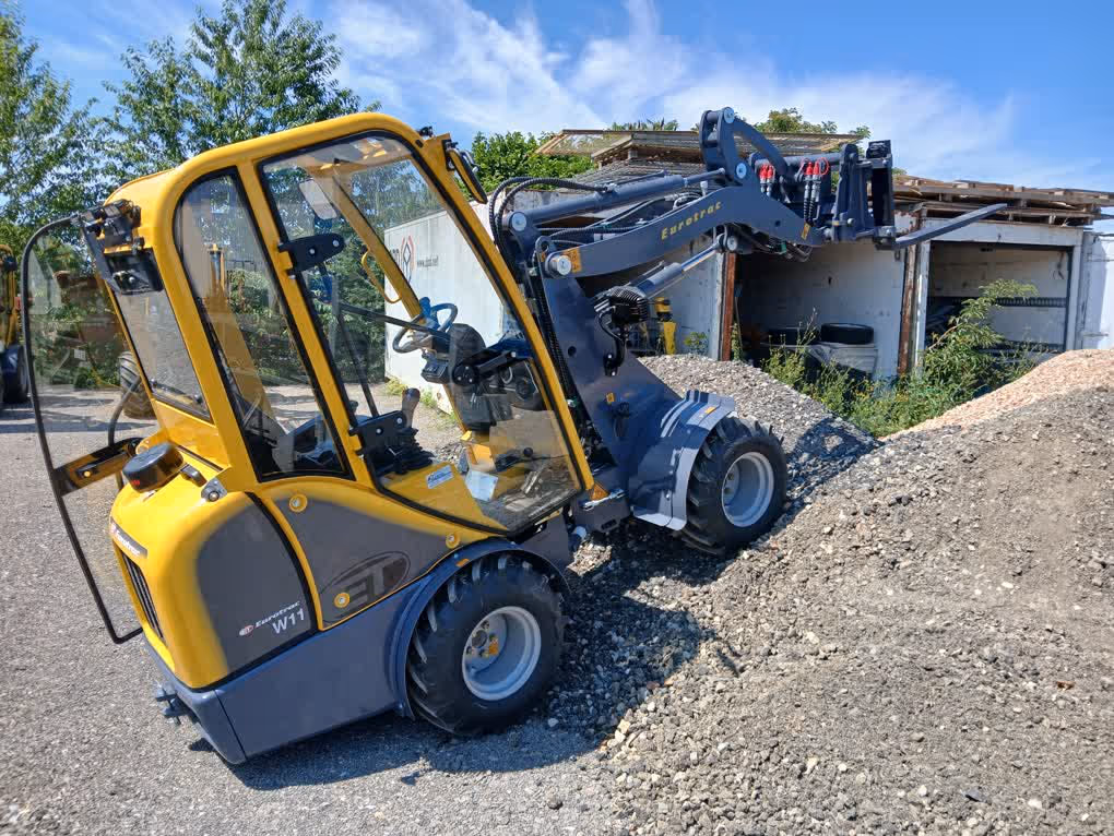 Eurotrac Baumaschine von Sadema GmbH im Einsatz, moderner Hoflader oder Minibagger mit Schaufel und Hydraulik, gelbes robustes Fahrzeug auf Baustelle oder Hof, kompakte Bauweise, starke Leistung und zuverlässige Technik für Landwirtschaft und Bau.