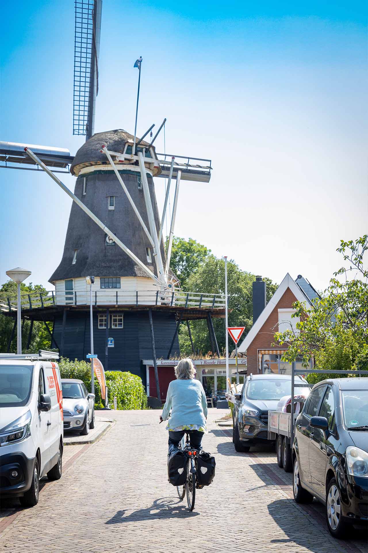 mevrouw fietst richting molen het roode hert