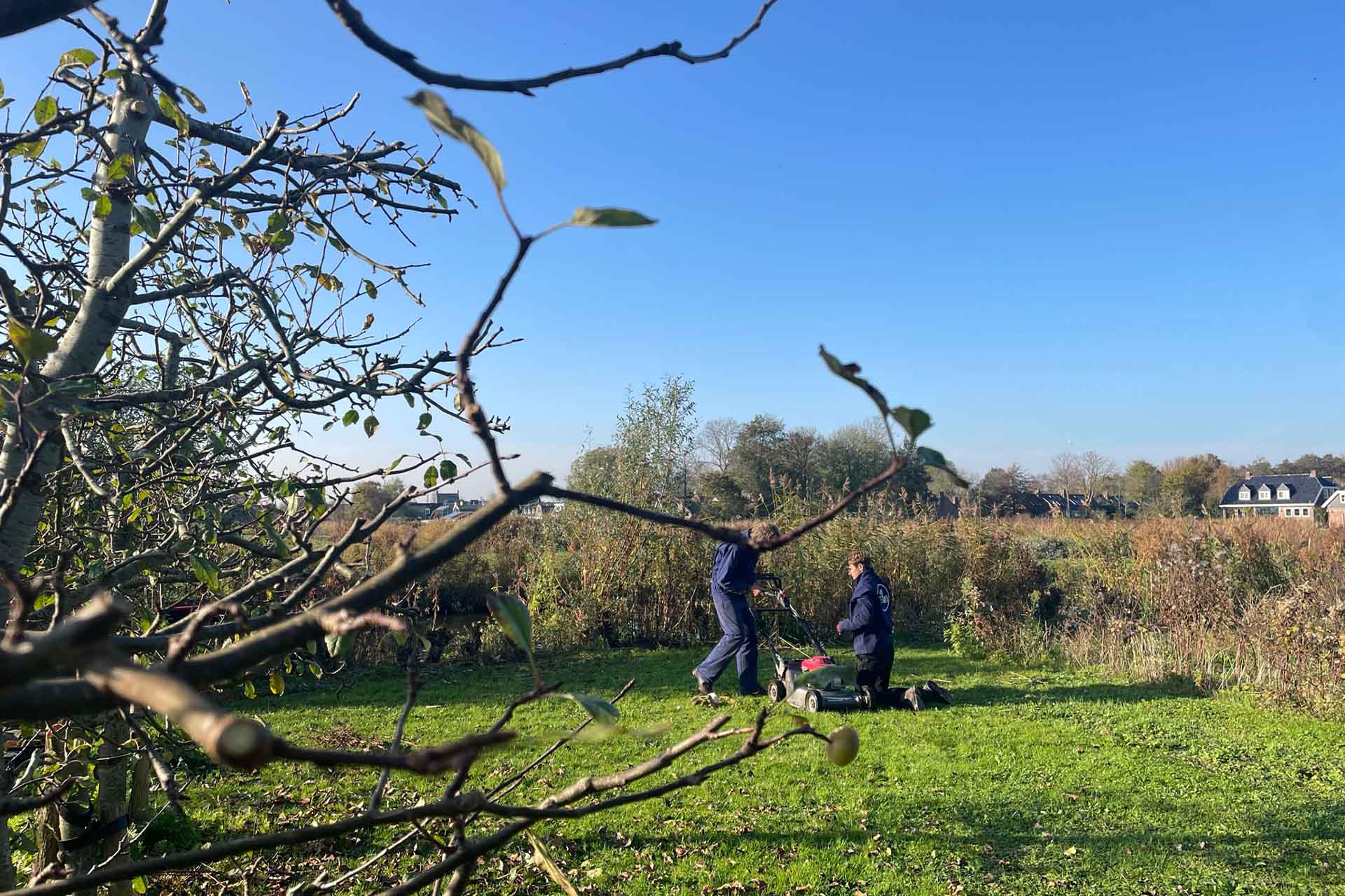 bewoner en medewerker maaien buiten het gras bij oosterheem