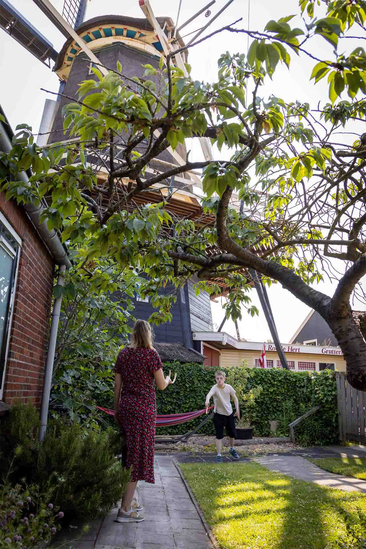kind en medewerker gooien een bal over bij molenhuis