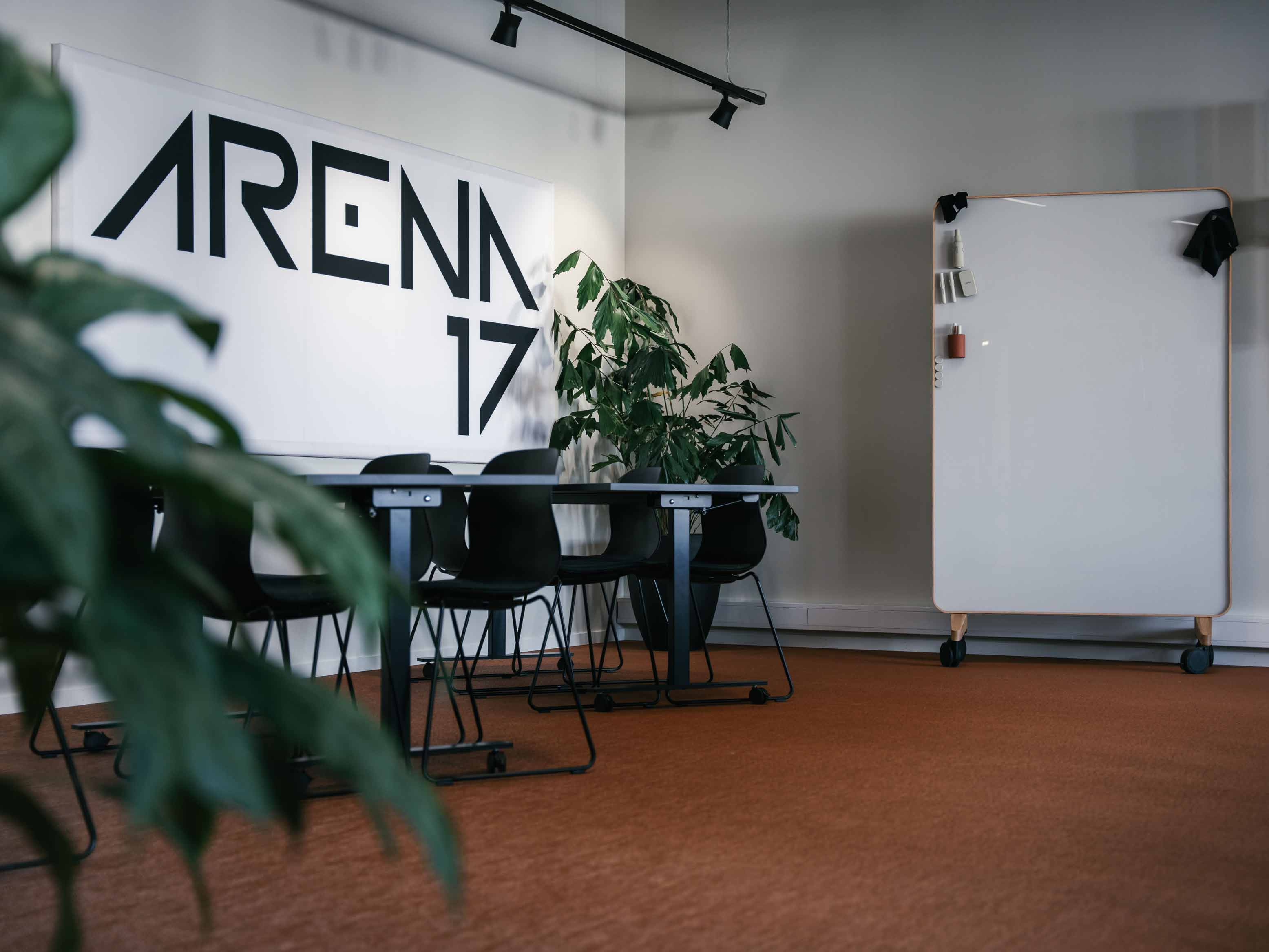 Arena 17-logo på veggen bak bord og en mobil whiteboard