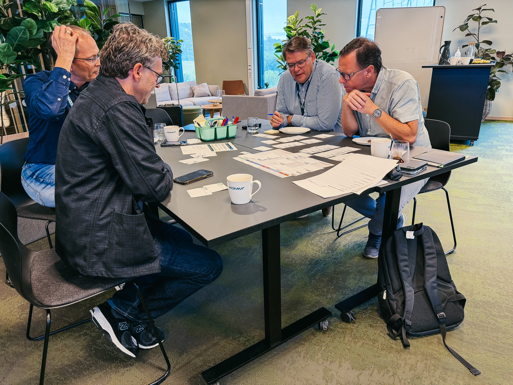 Fire menn diskuterer over papirer rundt et bord