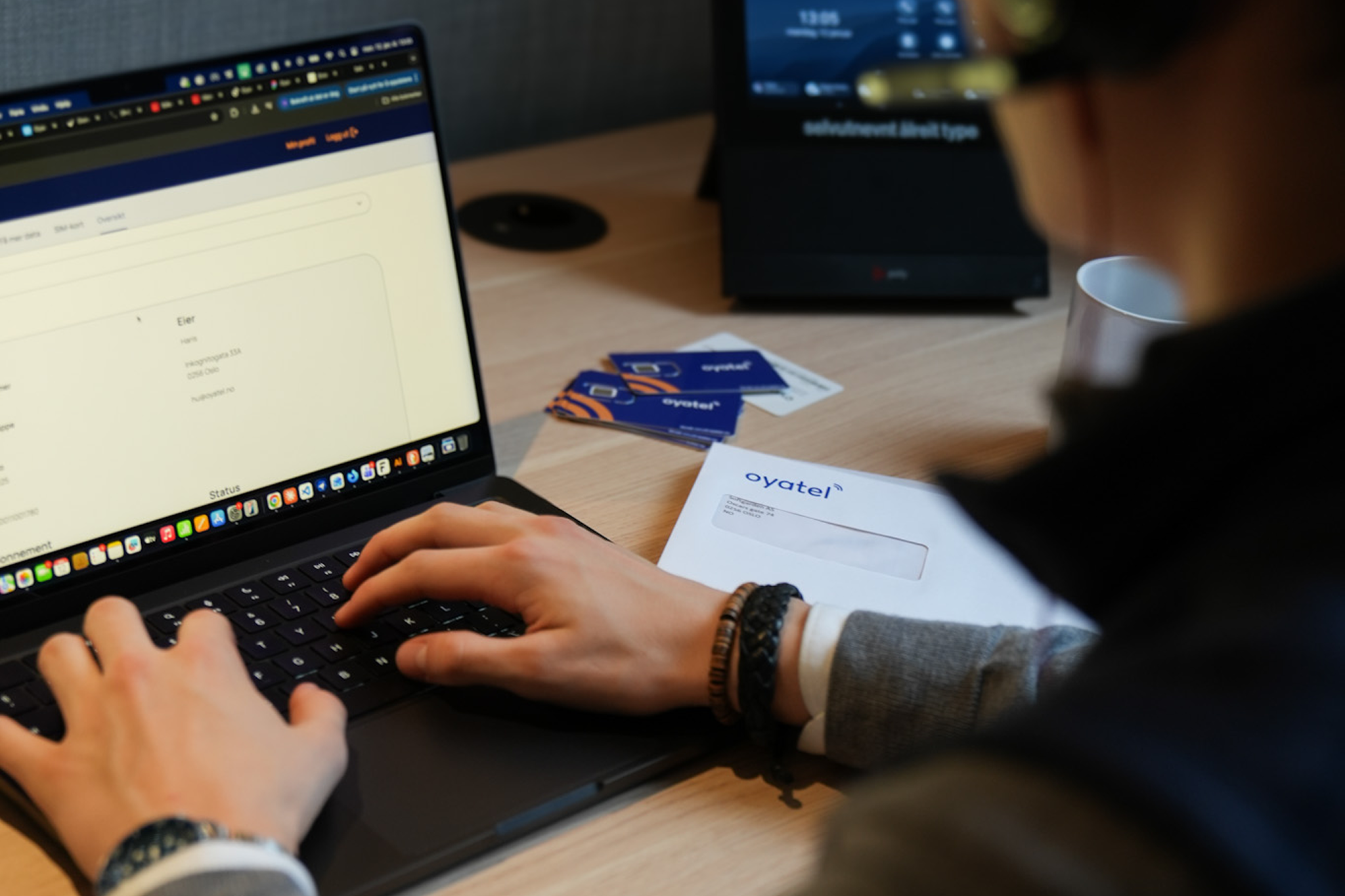 Ansatt som jobber på laptop med Oyatel SIM-kort på pulten