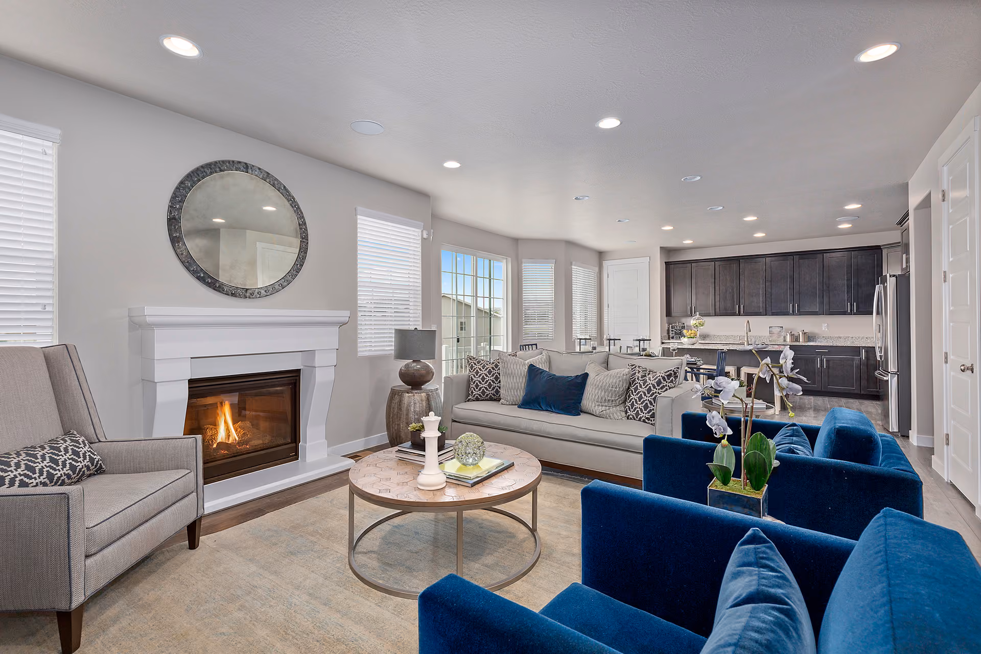 Living room with a fireplace, gray sofa, blue chairs, and a round coffee table with decor.