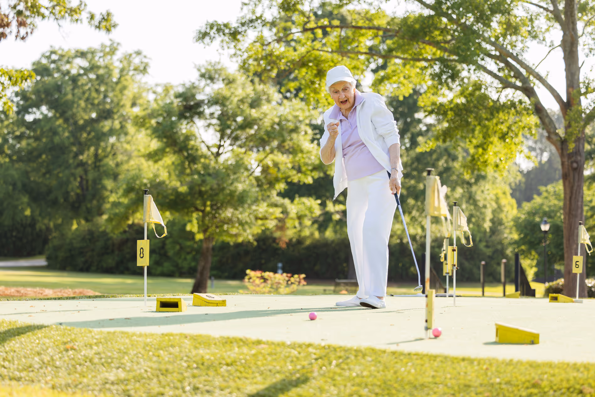 A person celebrates after putting a golf ball into the hole on a sunny day.