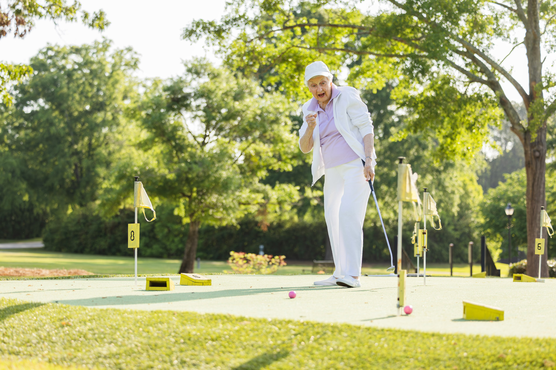 A person celebrates after putting a golf ball into the hole on a sunny day.