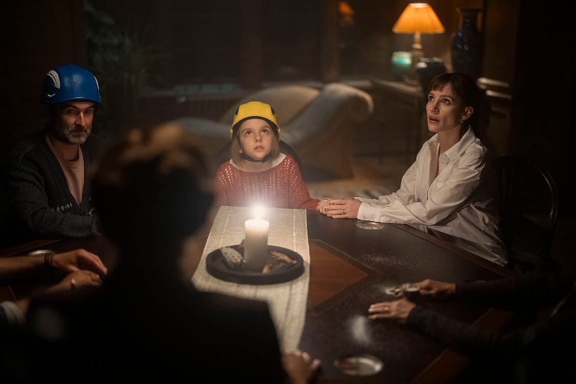 A family gathered around a candlelit table in Other Mommy, a Universal Pictures promotional still.