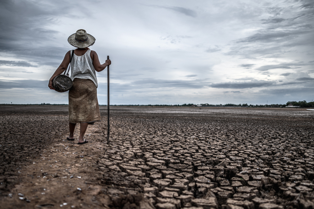 Person walking across cracked dry ground
