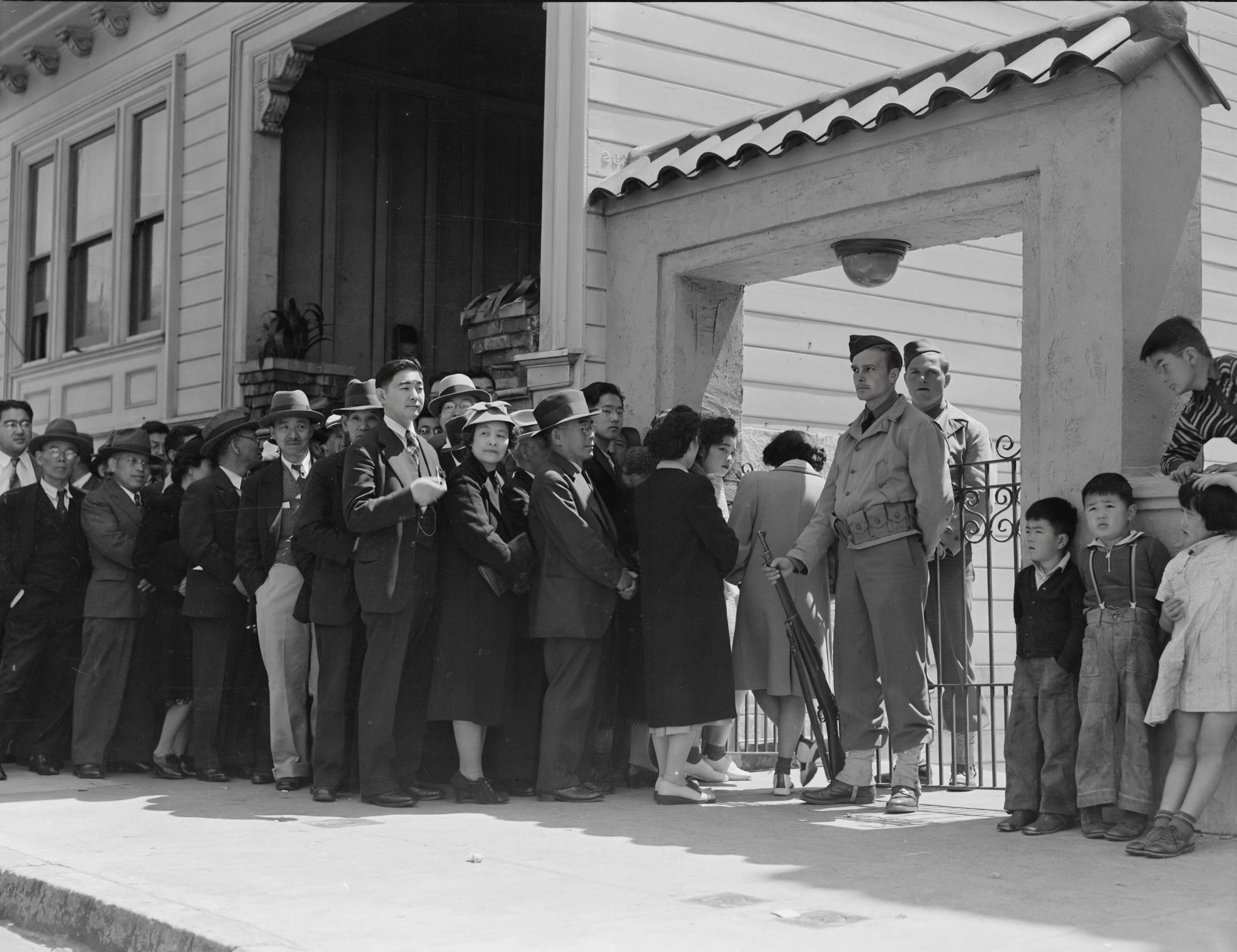 Historical photograph of people waiting outside a building
