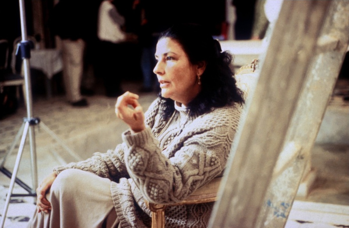 Baya Mahieddine seated beside her artwork