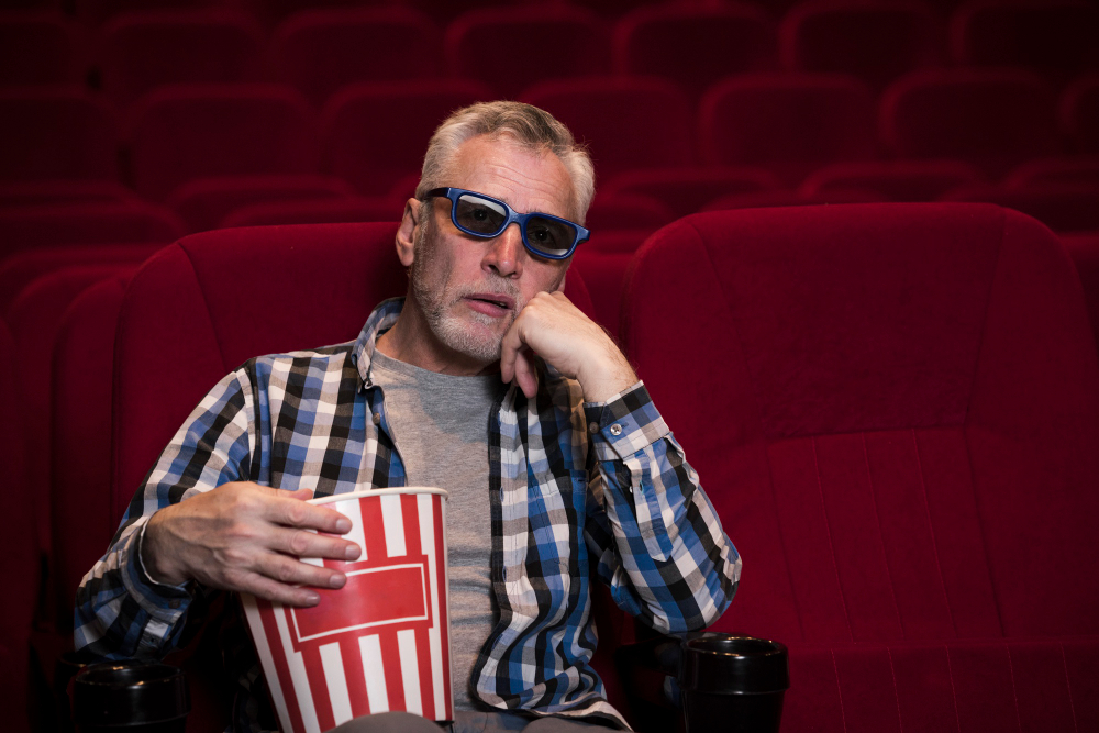 Cinema audience member wearing 3D glasses and holding popcorn