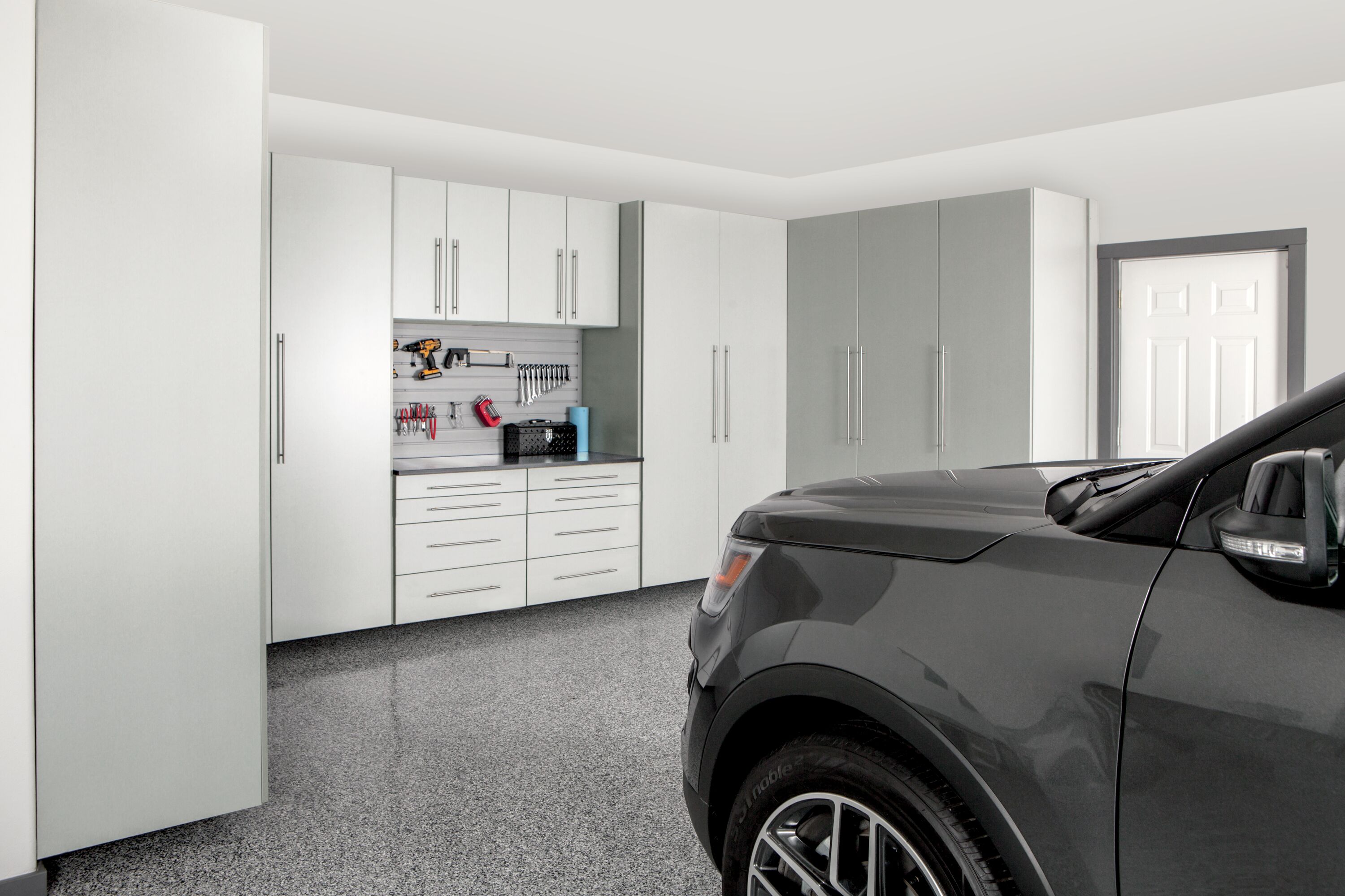 Car parked in a garage with white cabinets. 