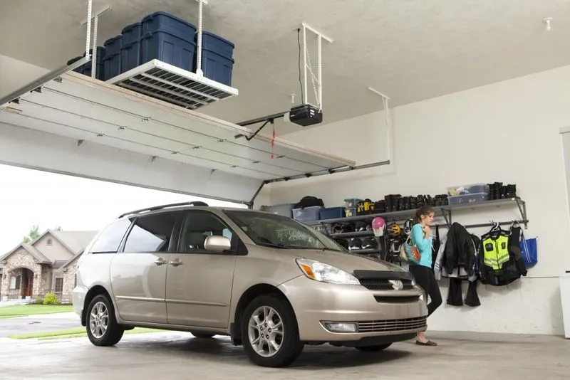 car parked in an organized garage with overhead shelving and hooks. 